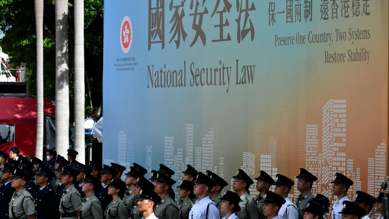 Attendees from various forces stand next to a banner supporting the new national security law during a flag-raising ceremony to mark China's National Day celebrations early morning in Hong Kong on July 1, 2020.
