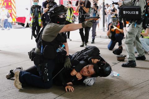 A police officer raises his pepper spray gun as he detains a man during a march on July 1.