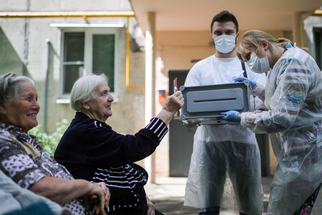 A woman shows her passport to election commission members during home voting.