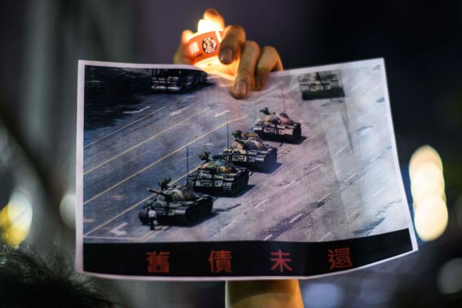 A man holds up the iconic Tiananmen Square <a href="index.php?page=&url=https%3A%2F%2Fwww.cnn.com%2Finteractive%2F2019%2F05%2Fworld%2Ftiananmen-square-tank-man-cnnphotos%2F" target="_blank">"Tank Man" photo</a> during the Victoria Park rally.