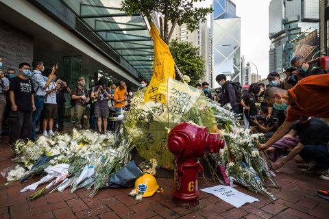 Pro-democracy activists leave flowers outside a shopping mall where a man fell to his death last year after hanging a protest banner.