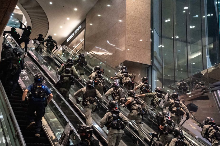 Police officers charge up shopping-mall escalators during demonstrations on July 1.