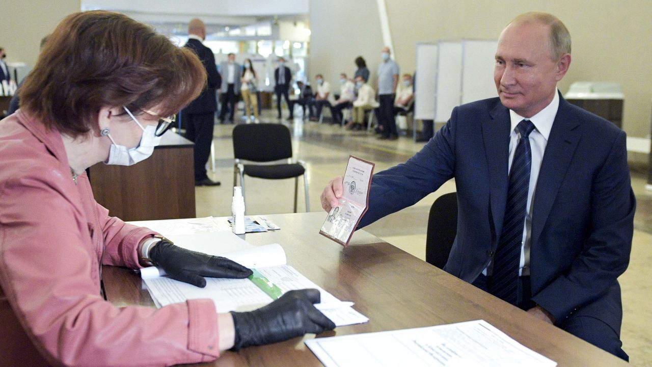 Russian President Vladimir Putin shows his passport to a member of an election commission as he arrives to take part in voting at a polling station in Moscow, Russia, Wednesday, July 1, 2020. The vote on the constitutional amendments that would reset the clock on Russian President Vladimir Putin's tenure and enable him to serve two more six-year terms is set to wrap up Wednesday. (Alexei Druzhinin, Sputnik, Kremlin Pool Photo via AP)