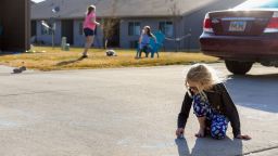 Apr 6, 2020; Sioux Falls, SD USA; Lexus Larson, 8, draws with sidewalk chalk outside her house while her friends, Maliah, 10, and Makinley Walsh, 7, play in their own yard across the street on Monday, April 6, in Sioux Falls, SD. While the girls have played together most days before the coronavirus pandemic, Larson's mother has now told her not to cross the middle line in the concrete as a social distancing measure. Mandatory Credit: Erin Bormett/Argus Leader via USA TODAY NETWORK