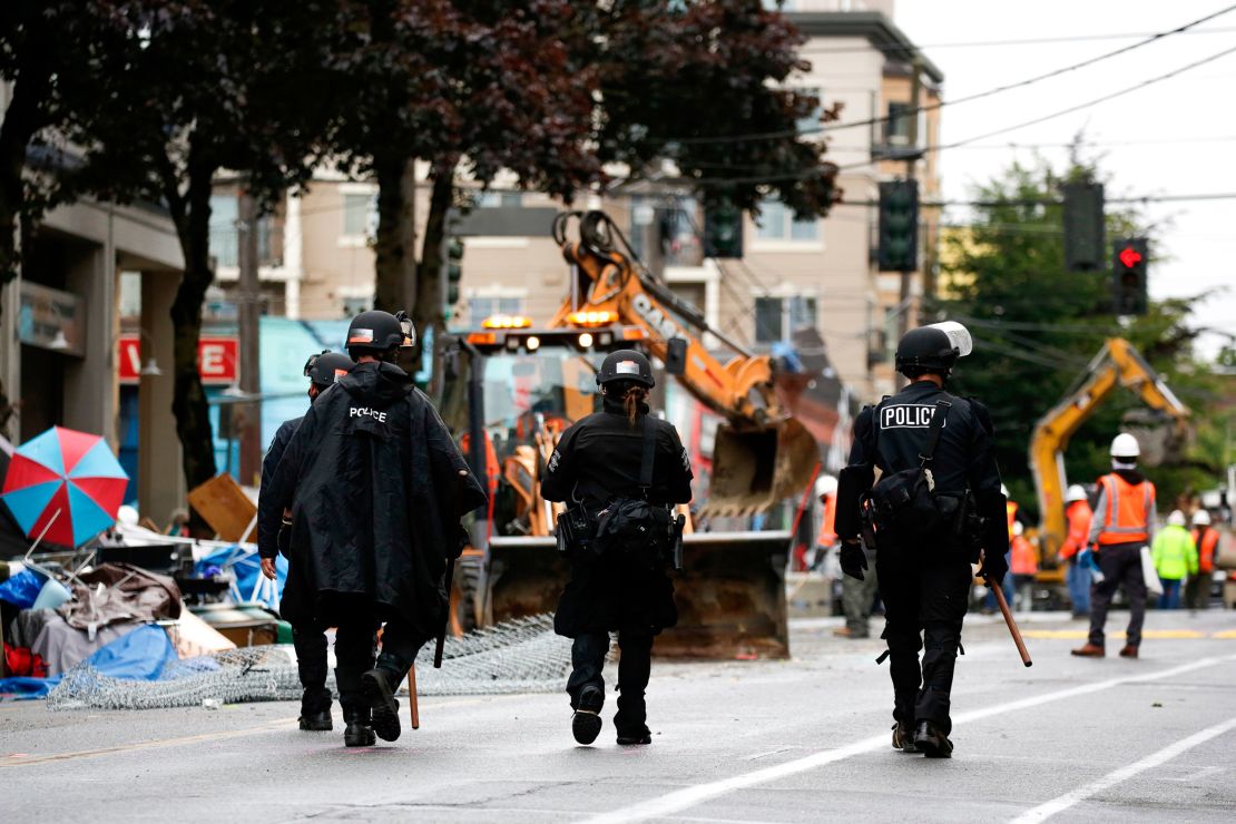 Seattle police walk past debris and bulldozing equipment near the East Precinct on July 1 after police cleared the CHOP.