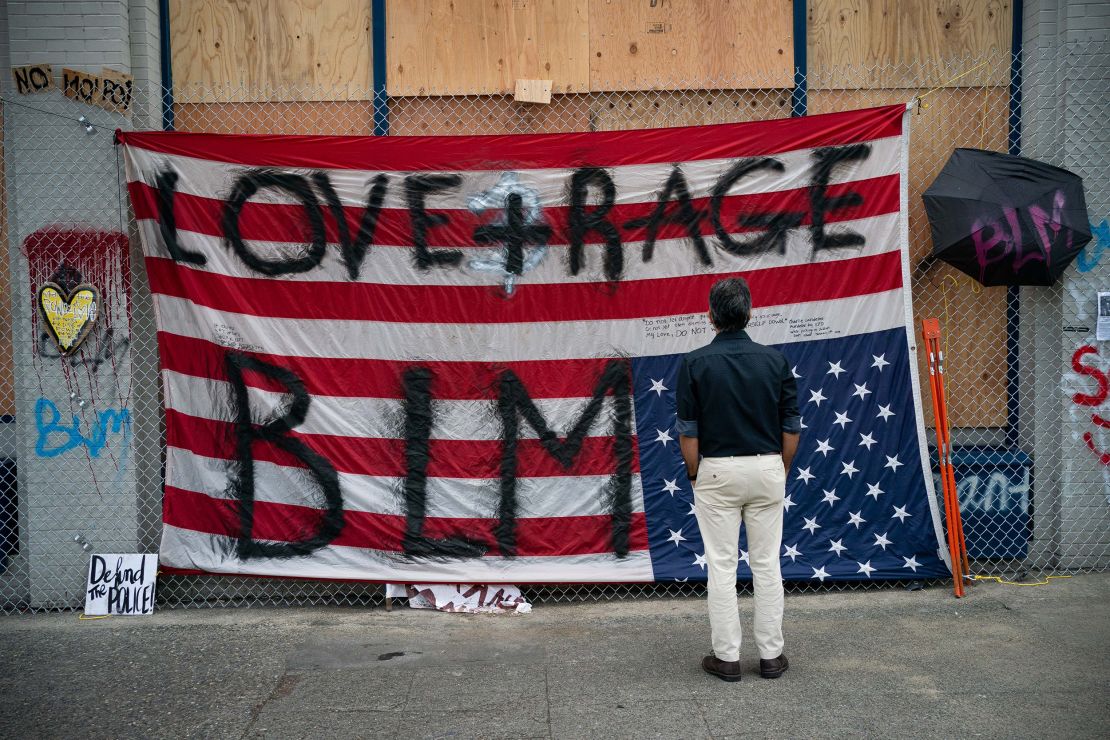 A man views an upside down US flag at the Seattle Police Department's vacated East Precinct on June 14 in the CHOP.