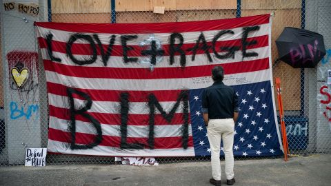 A man views an upside down US flag at the Seattle Police Department's vacated East Precinct on June 14 in the CHOP.