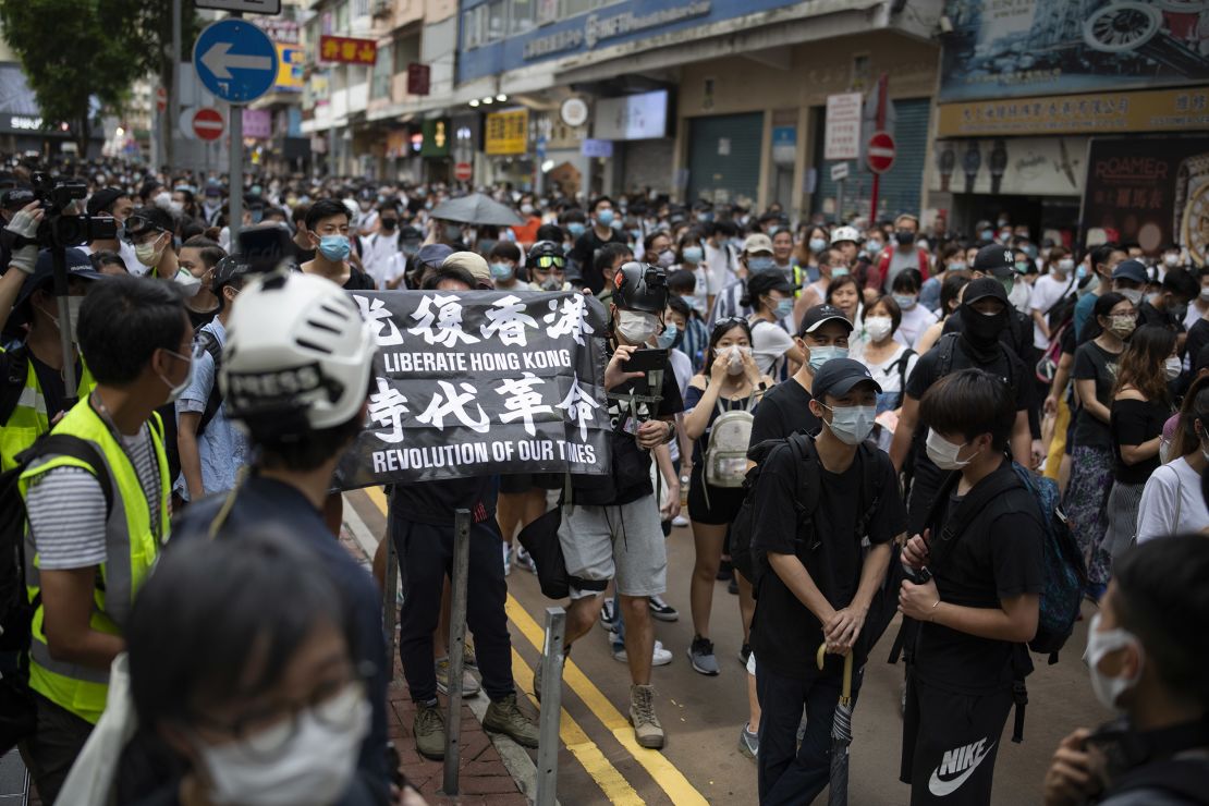 Passers-by and protesters gather in Causeway Bay, Hong Kong. A protester is seen carrying a flag that says "Liberate Hong Kong, revolution of our times," an act that could now be considered a crime under the city's new national security law.