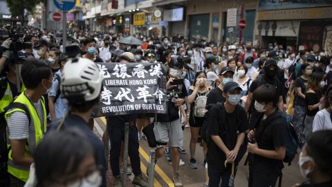 Passers-by and protesters gather in Causeway Bay, Hong Kong. A protester is seen carrying a flag that says "Liberate Hong Kong, revolution of our times," an act that could now be considered a crime under the city's new national security law.