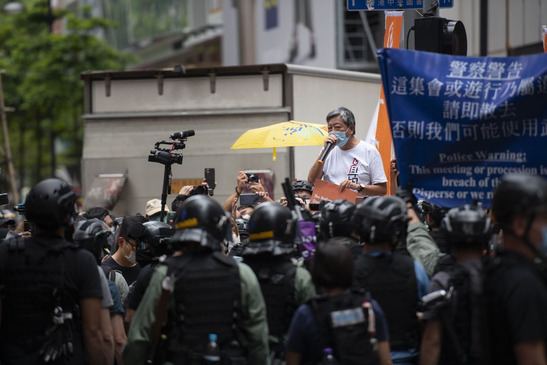 Former lawmaker and longtime activist Lee Cheuk-Yan is seen addressing a crowd in Causeway Bay as riot police stand in the background. He was arrested soon after.