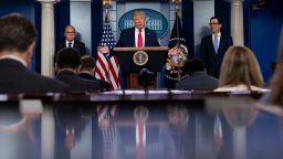 President Donald Trump speaks during a news briefing at the White House, Thursday, July 2, 2020, in Washington, as White House chief economic adviser Larry Kudlow, left, and Treasury Secretary Steven Mnuchin, look on. 
