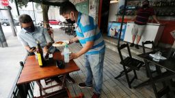 A waiter serves a customer at a bar after the reopening of gyms, restaurants and sport facilities on the beaches as the city eases restrictions, amid the coronavirus disease (COVID-19) outbreak in Rio de Janeiro, Brazil July 2, 2020. 