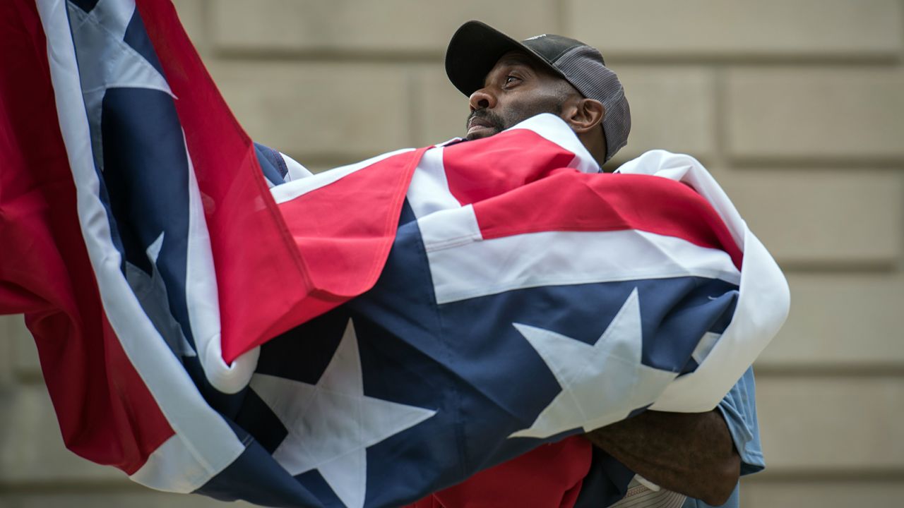 A staff member raises the state flag for the flag retirement ceremony at the Mississippi State Capitol building in Jackson, Mississippi on July 1, 2020. (Photo by Rory Doyle / AFP)