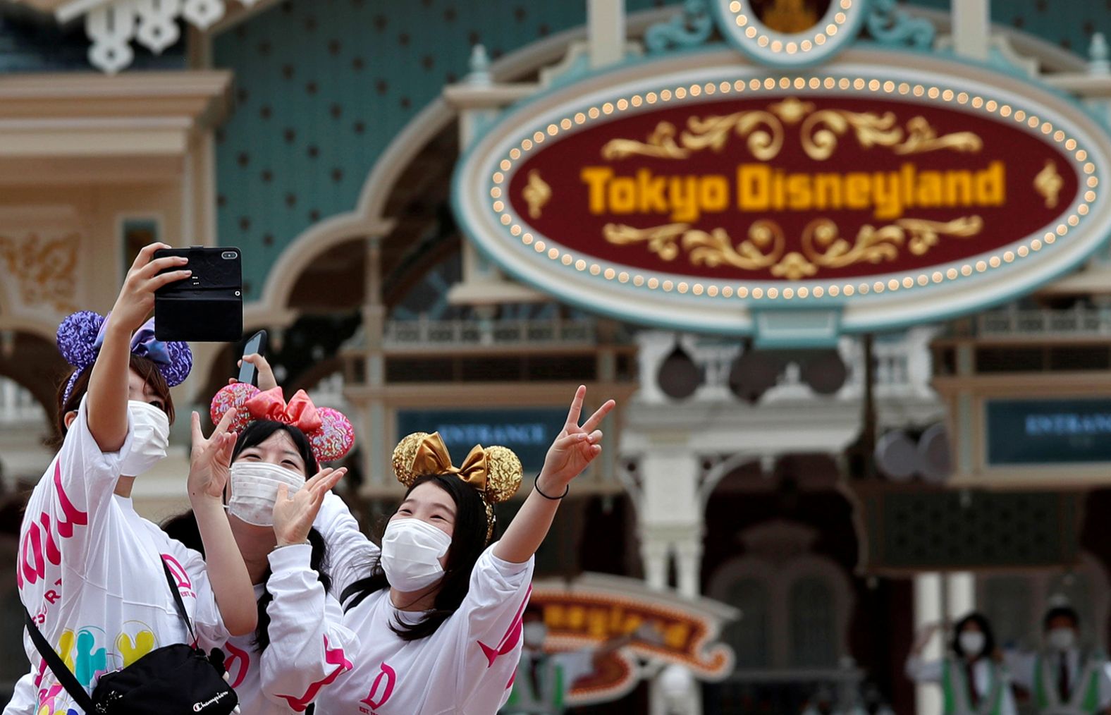 Visitors take a selfie at the entrance gate of Tokyo Disneyland on July 1. <a  target="_blank">Tokyo Disneyland</a> and Tokyo Disney Sea are reopening after months of being closed because of the pandemic. All of Disney's Asia parks have now officially reopened.