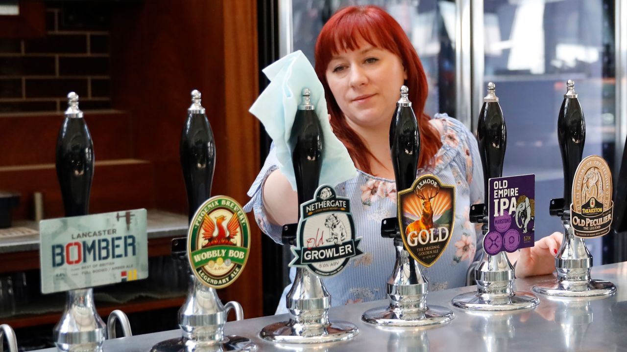 A member of staff at a Wetherspoons pub in north London cleans the bar in preparation for pubs to reopen early next month on June 24, 2020. - Prime Minister Boris Johnson yesterday announced a further easing of coronavirus restrictions in England from July 4, as part of plans to kickstart hospitality, culture and tourism.