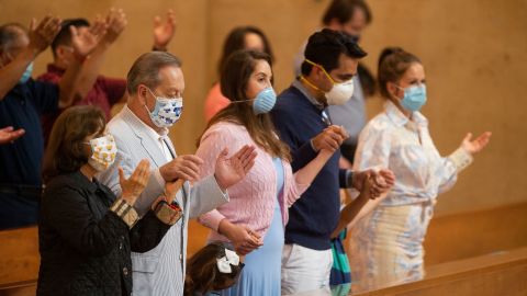 Family members hold hands as they pray at the first English Mass with faithful present at the Cathedral of Our Lady of the Angels in downtown Los Angeles on Sunday, June 7, 2020.