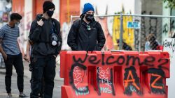 SEATTLE, WASHINGTON - JUNE 14: Two people stand at an entrance to the âCapitol Hill Organized Protestâ formerly known as the âCapitol Hill Autonomous Zoneâ in Seattle, Washington on June 14, 2020. The âCapitol Hill Organized Protestâ was formed after Seattle Police abandoned its East Precinct during protests against police brutality and the death of George Floyd, an unarmed black man who died after being pinned down by a white police officer in Minneapolis, Minnesota, United States on May 25, 2020. (Photo by Noah Riffe/Anadolu Agency via Getty Images)