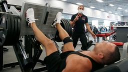 A trainer, top, at Mountainside Fitness, works with a client as the facility remains open even as Arizona Gov. Doug Ducey has issued an executive order for all gyms to close due to the surge in coronavirus cases in Arizona Thursday, July 2, 2020, in Phoenix. For the third straight day, several health clubs in metro Phoenix were defying Ducey's 30-day shutdown order to close gyms, bars, water park and tubing businesses, raising questions about whether officials who have been criticized for responding indecisively to the pandemic will be effective in shutting down the clubs. (AP Photo/Ross D. Franklin)