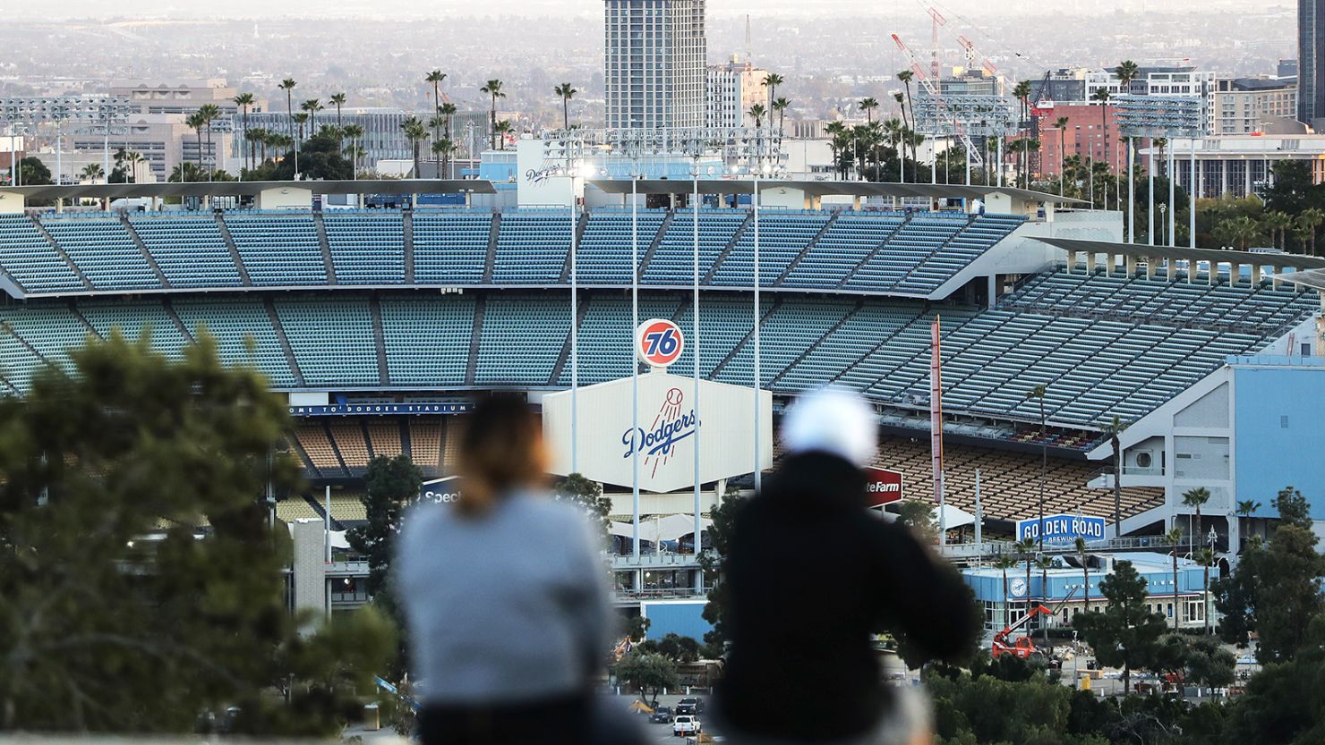 People sit on a hill overlooking Dodger Stadium in Los Angeles, where this year's All-Star Game would have taken place.