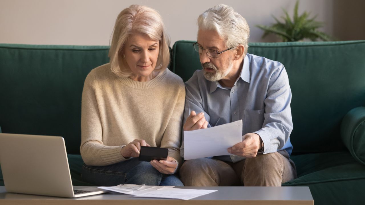 Two people looking at financial papers and a calculator.