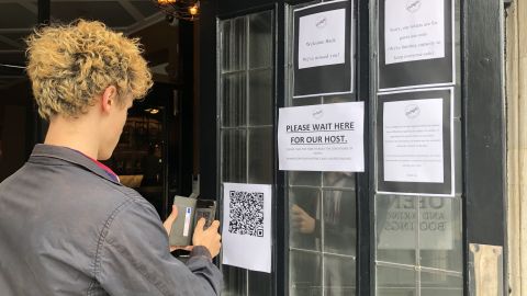 A drinker scans a QR code in order to enter contact-tracing details before entering a south London pub.