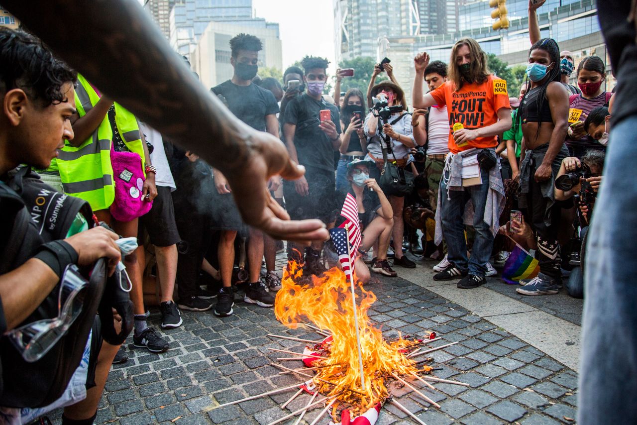 A man throws an American flag into a fire during protests at Columbus Circle in New York.