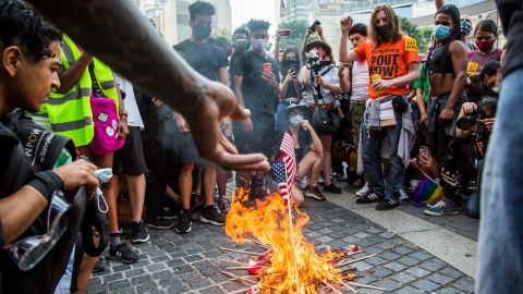 A man throws an American flag into a fire during protests at Columbus Circle in New York.