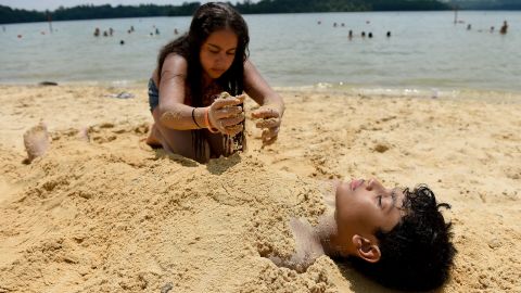 Malyah Guzman, 11, buries her cousin Jhadieo Guzman, 12, in the sand at Blue Marsh Lake in Bern Township, Pennsylvania.