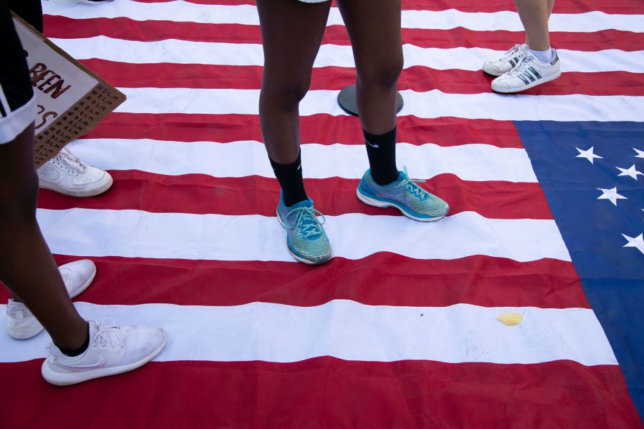 Demonstrators stand on an American Flag while protesting racial injustice at Black Lives Matter Plaza in Washington, DC.