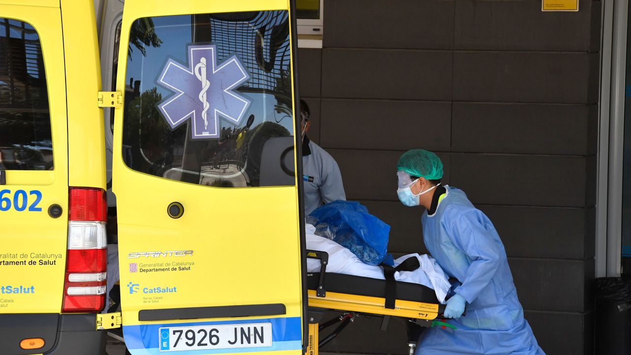 A healthcare worker carries a patient out of an ambulance outside the Arnau de Vilanova University Hospital in Lleida on July 4, 2020. - Spain's northeastern Catalonia region locked down an area with around 200,000 residents around the town of Lerida following a surge in cases of the new coronavirus.