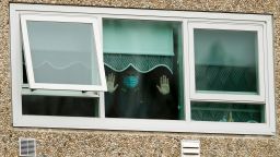MELBOURNE, AUSTRALIA - JULY 06: A man is seen looking out a window of the Flemington Towers Government Housing complex on July 06, 2020 in Melbourne, Australia. Nine public housing estates are in mandatory lockdown and two additional suburbs are under stay-at-home orders as authorities work to stop further COVID-19 outbreaks in Melbourne. The public housing towers will be in total lockdown for at least five days and the only people allowed in and out are those providing essential services. Residents of 12 Melbourne hotspot postcodes are also on stay-at-home orders and are only able to leave home have for exercise or work, to buy essential items including food or to access childcare and healthcare. Businesses and facilities in these lockdown areas are also restricted and cafes and restaurants can only open for takeaway and delivery. (Photo by Darrian Traynor/Getty Images)