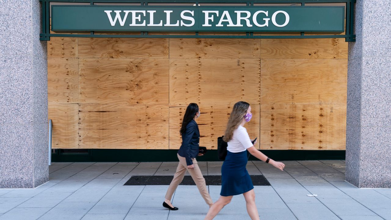 Women walk past the boarded up branch of a Wells Fargo bank in in Washington, DC, last summer.