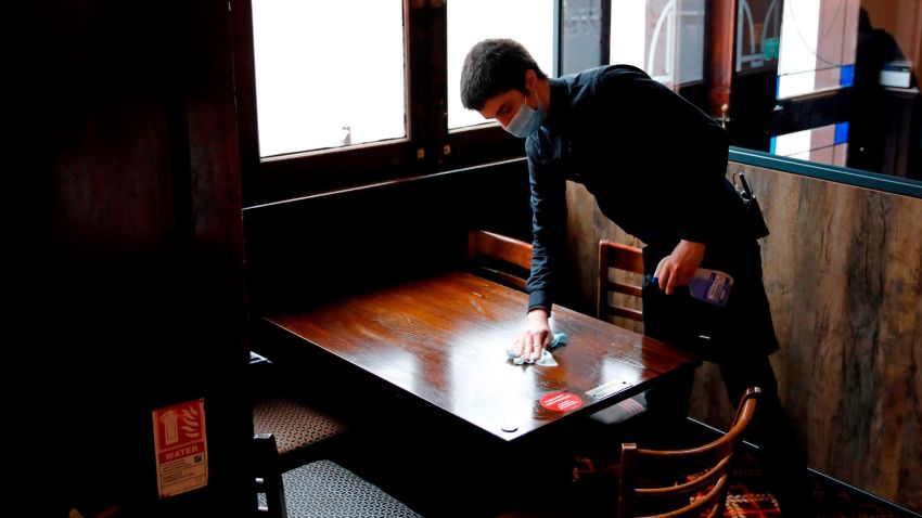 A member of bar staff wearing PPE (personal protective equipment) in the form of a face mask, cleans a table inside the Wetherspoon pub, Goldengrove in Stratford in east London on July 4, 2020, as restrictions are further eased during the novel coronavirus COVID-19 pandemic. - Pubs in England reopen on Saturday for the first time since late March, bringing cheer to drinkers and the industry but fears of public disorder and fresh coronavirus cases. (Photo by Tolga AKMEN / AFP) (Photo by TOLGA AKMEN/AFP via Getty Images)
