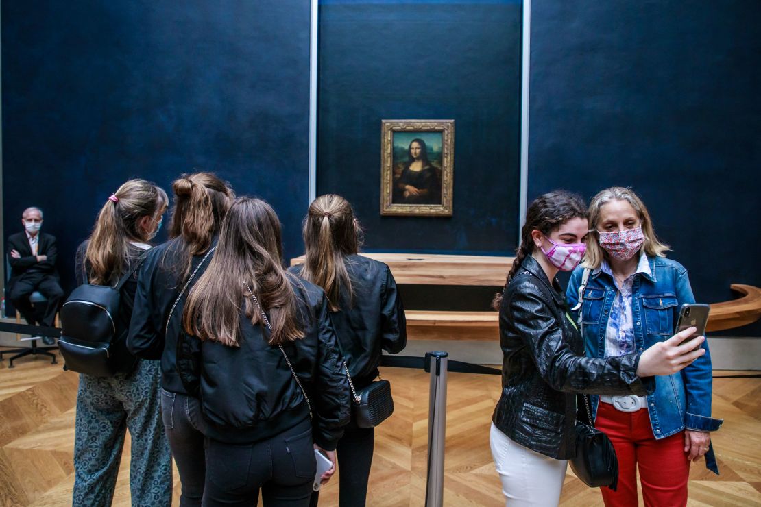 Visitors wearing face masks take photographs in front of the Mona Lisa at the Louvre Museum in Paris on July 6.