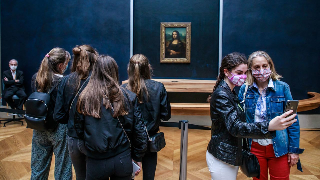 Visitors wearing face masks take photographs in front of the Mona Lisa at the Louvre Museum in Paris on July 6.