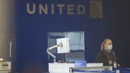 A United Airlines Holdings Inc. worker stands behind a protective plastic barrier at the company's check-in counter at Newark International Airport (EWR) in Newark, New Jersey, U.S., on Tuesday, June 9, 2020. Airline losses are surging to unprecedented levels expected to be more than three times those following the 2008 global economic slump, according to the industry's main trade group. Photographer: Angus Mordant/Bloomberg via Getty Images