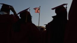 A US flag flies above a building as students earning degrees at Pasadena City College participate in the graduation ceremony, June 14, 2019, in Pasadena, California. - With 45 million borrowers owing $1.5 trillion, the student debt crisis in the United States has exploded in recent years and has become a key electoral issue in the run-up to the 2020 presidential elections."Somebody who graduates from a public university this year is expected to have over $35,000 in student loan debt on average," said Cody Hounanian, program director of Student Debt Crisis, a California NGO that assists students and is fighting for reforms. (Photo by Robyn Beck / AFP)        (Photo credit should read ROBYN BECK/AFP via Getty Images)
