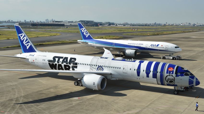 An All Nippon Airways (ANA) Boeing 787-9 aircraft in the livery of Star Wars droid character R2-D2 (front) is seen on the tarmac at Tokyo's Haneda airport on October 14, 2015, as part of the company's Star Wars project. The Boeing aircraft is scheduled to go into service on international routes after a fan appreciation flight event on October 17. / AFP / KAZUHIRO NOGI        (Photo credit should read KAZUHIRO NOGI/AFP via Getty Images)