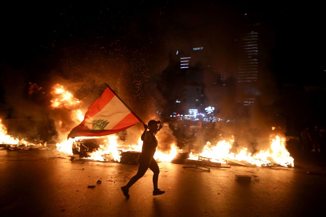 A protester holding the Lebanese flag runs as protesters block the Jounieh Tripoli highway with flaming tires in Jal el Dib, northeast of Beirut on June 11.