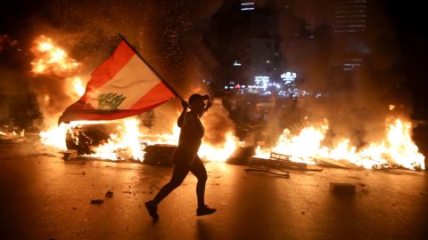 A protester holding the Lebanese flag runs as protesters block the Jounieh Tripoli highway with flaming tires in Jal el Dib, northeast of Beirut on June 11.