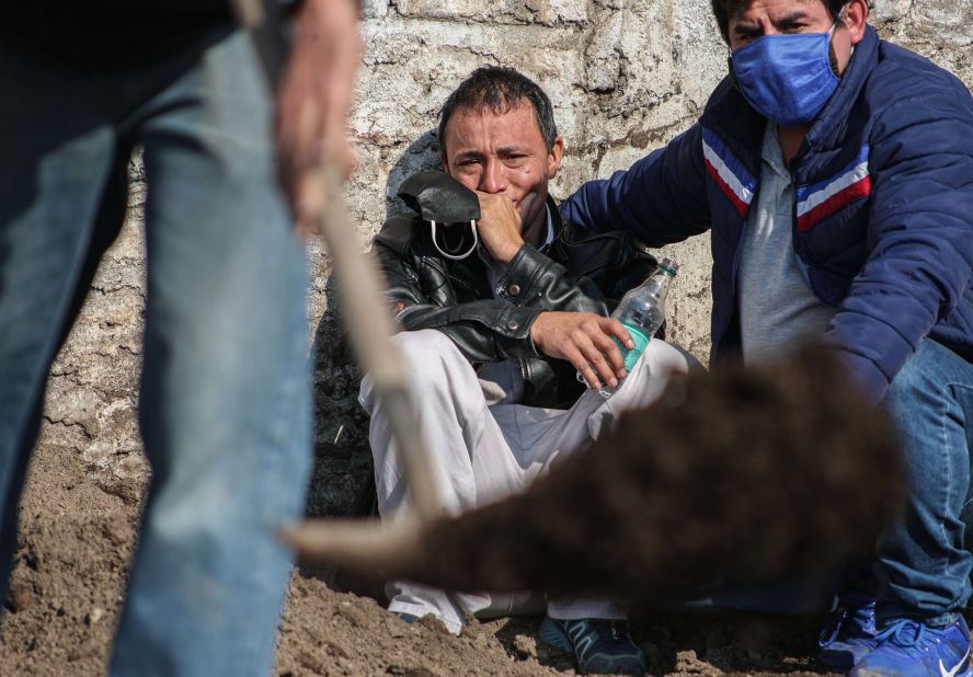 Peruvian migrant Jose Collantes cries as he watches cemetery workers bury his wife, Silvia Cano, in Santiago, Chile, on July 3. She died of coronavirus complications, according to Collantes.