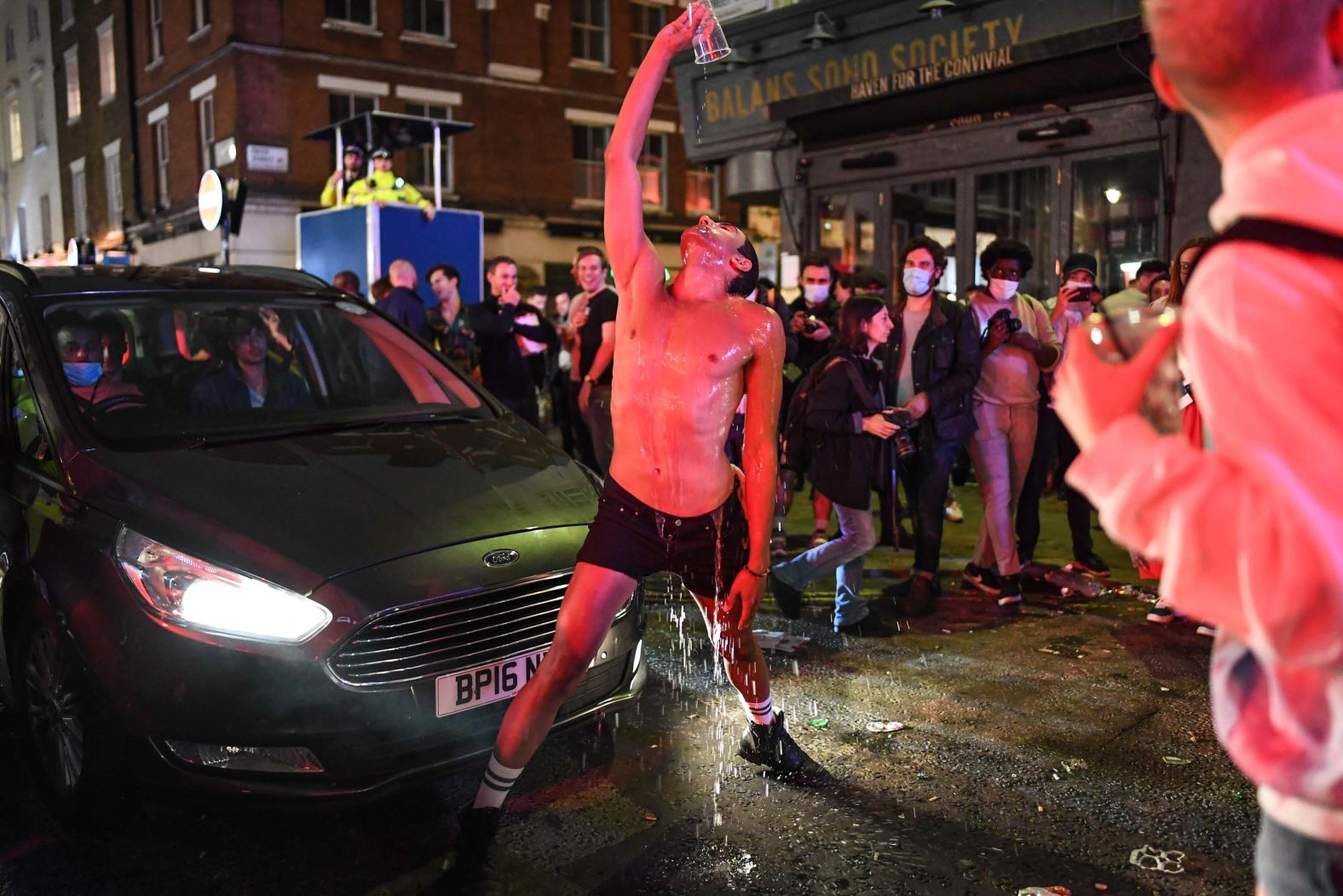 A man pours water over himself in London's Soho neighborhood on July 4 — the day pubs, hotels and restaurants <a  target="_blank">were allowed to reopen</a> in the United Kingdom.