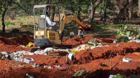 A backhoe has been brought in to dig more graves at the Vila Formosa cemetery in São Paulo.