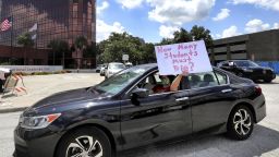 A teacher holds up a sign while driving by the Orange County Public Schools headquarters as educators protest in a car parade around the administration center in downtown Orlando, Fla., Tuesday, July 7, 2020. OCPS teachers are protesting the decision by Gov. Ron DeSantis and the state education commissioner mandating that all public schools open in August despite the spike in coronavirus cases in Florida. (Joe Burbank/Orlando Sentinel via AP)