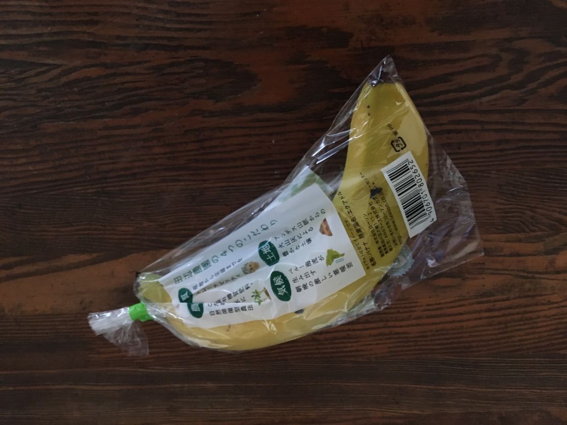 A single banana is swaddled tightly plastic wrapping.