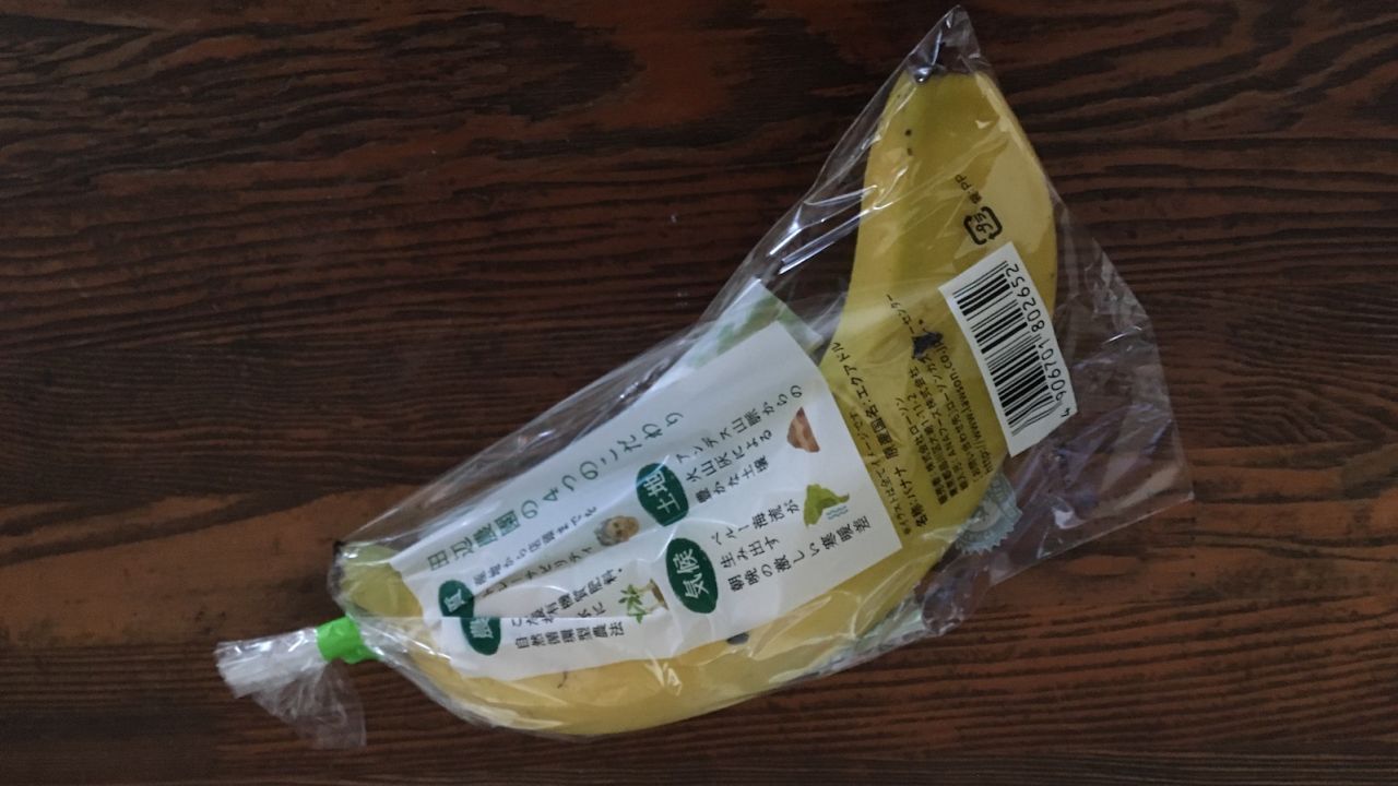 A single banana is swaddled tightly plastic wrapping.
