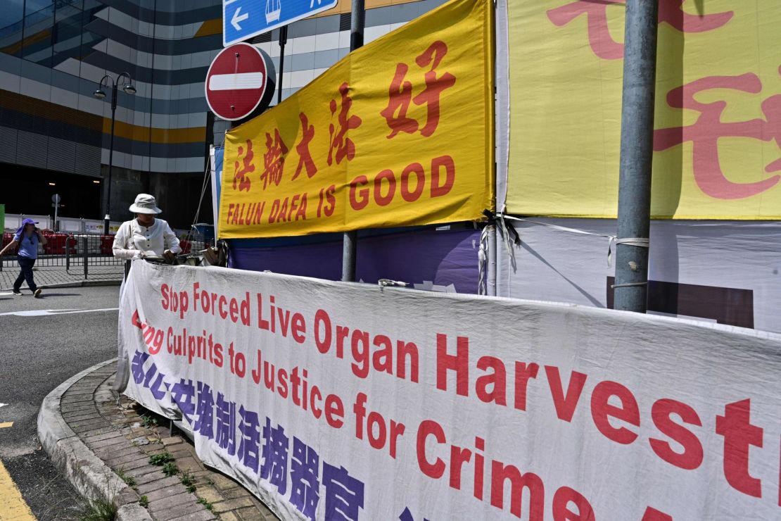 A woman adjusts banners in support of Falun Gong in Tung Chung, an area popular with tourists from the mainland, in Hong Kong on April 25, 2019.