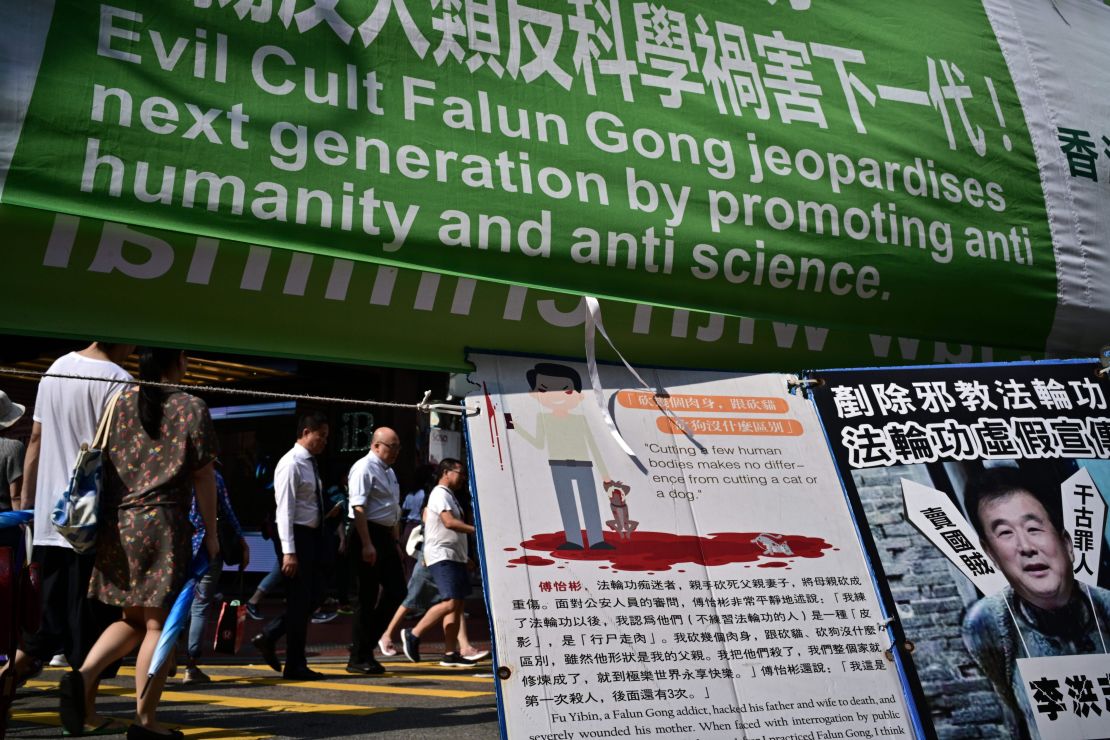 Pedestrians walk past banners criticising the Falun Gong spiritual movement displayed along a pavement in Causeway Bay, a popular shopping district, in Hong Kong on April 25, 2019.