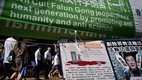 Pedestrians walk past banners criticising the Falun Gong spiritual movement displayed along a pavement in Causeway Bay, a popular shopping district, in Hong Kong on April 25, 2019.