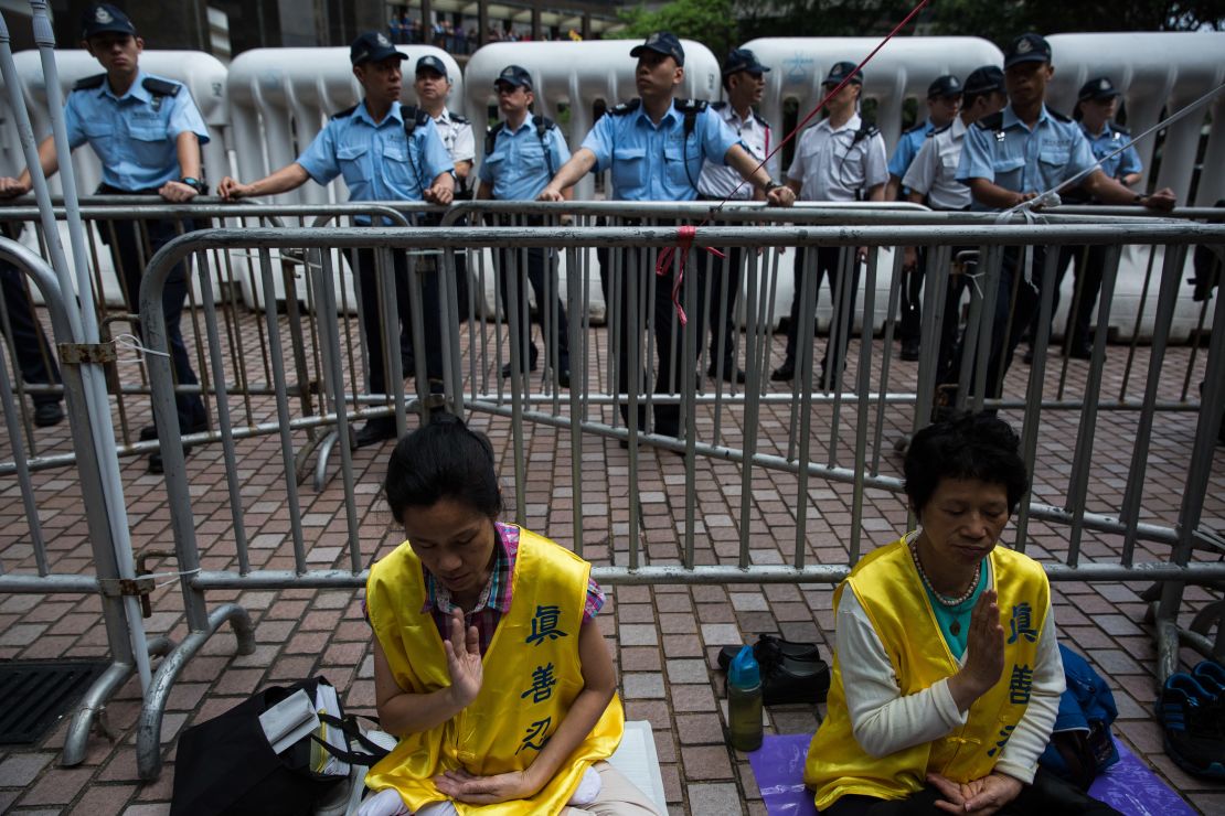 Falun Gong members meditate as policemen watch demonstrators during a pro-democracy protest in Hong Kong on May 18, 2016.